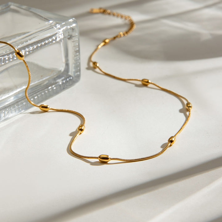 Gold Dainty Bead Necklace laid flat, showing the beads and extender chain