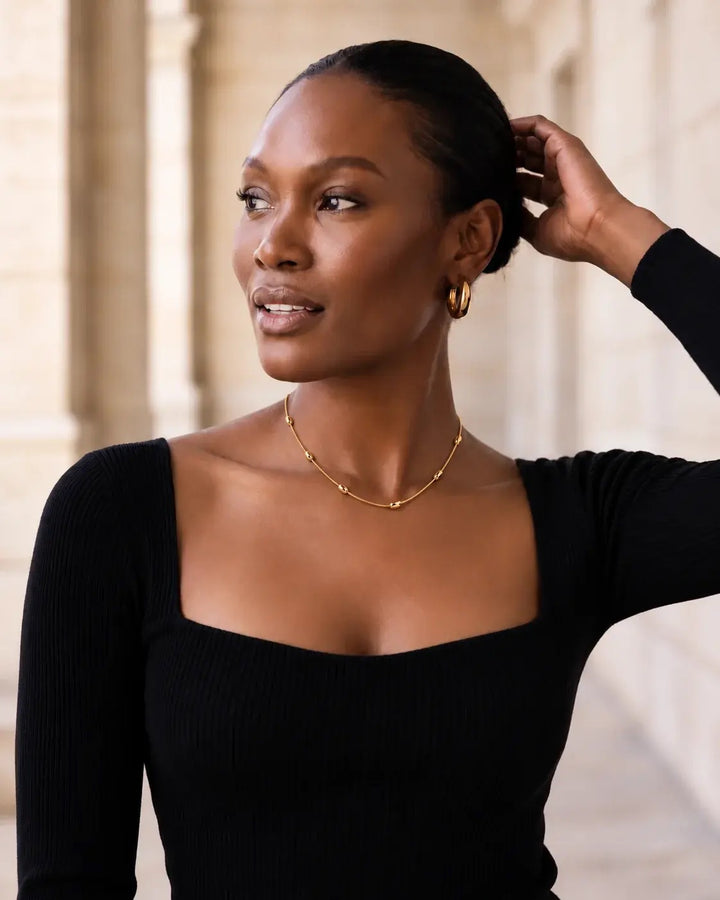 Model wearing the Gold Dainty Bead Necklace with a black square-neck top