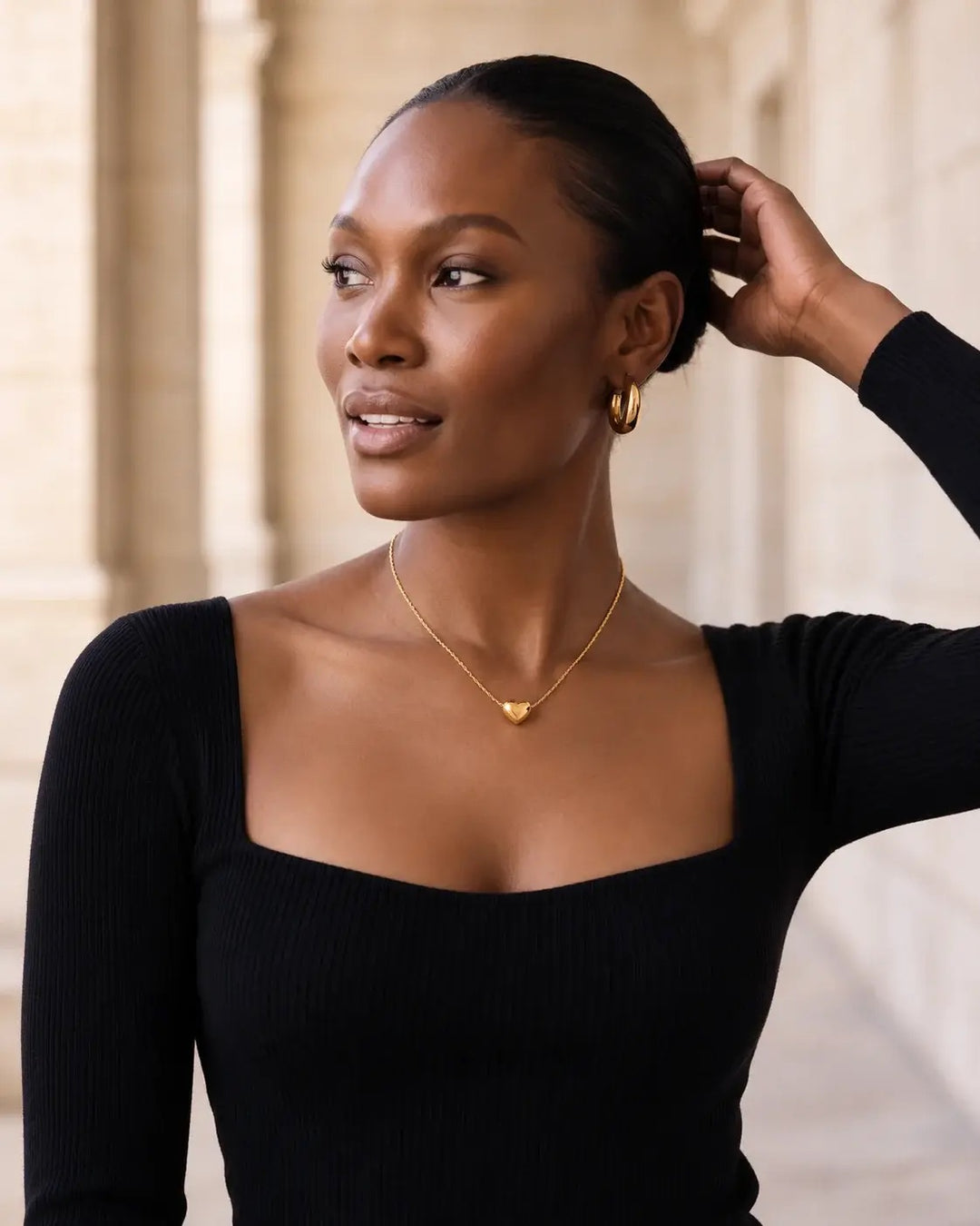 Model wearing the Gold Mini Heart Necklace with a black square-neck top
