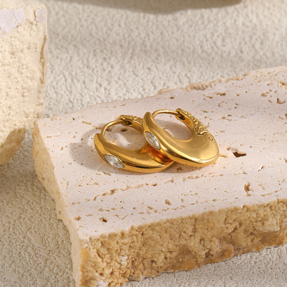Gold Mini Solitaire Huggies resting together on stone, showing the textured hinge