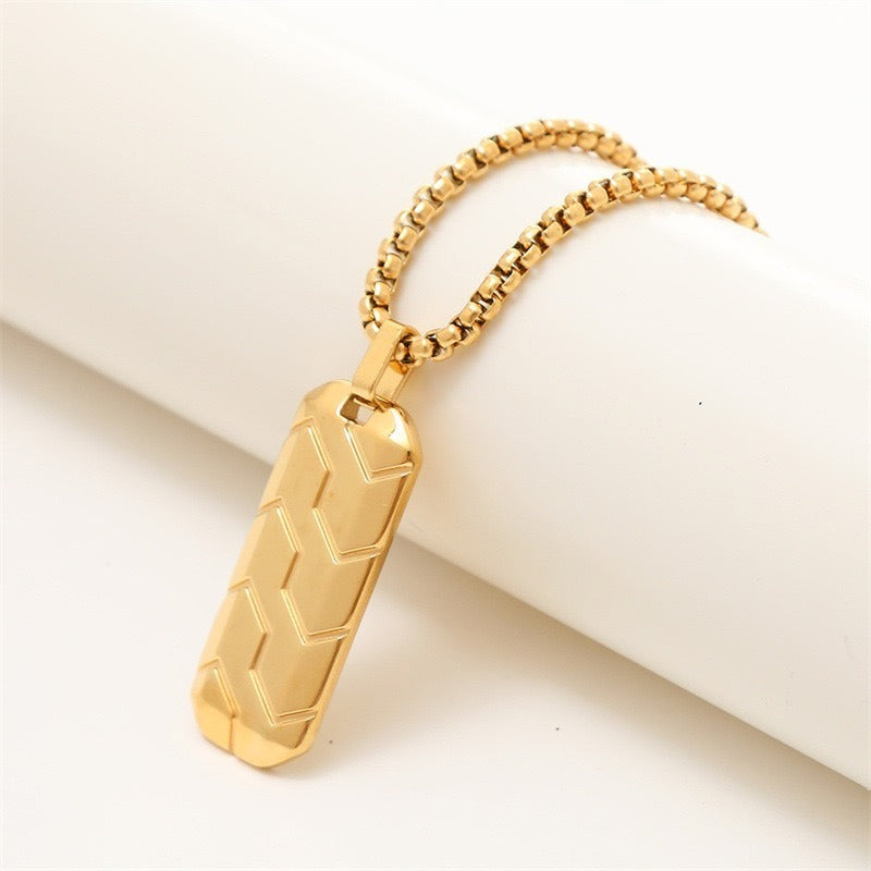 Gold Chevron Pendant with chain draped over a white cylinder