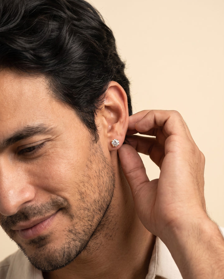 Man touching his ear to show the gold stud earring