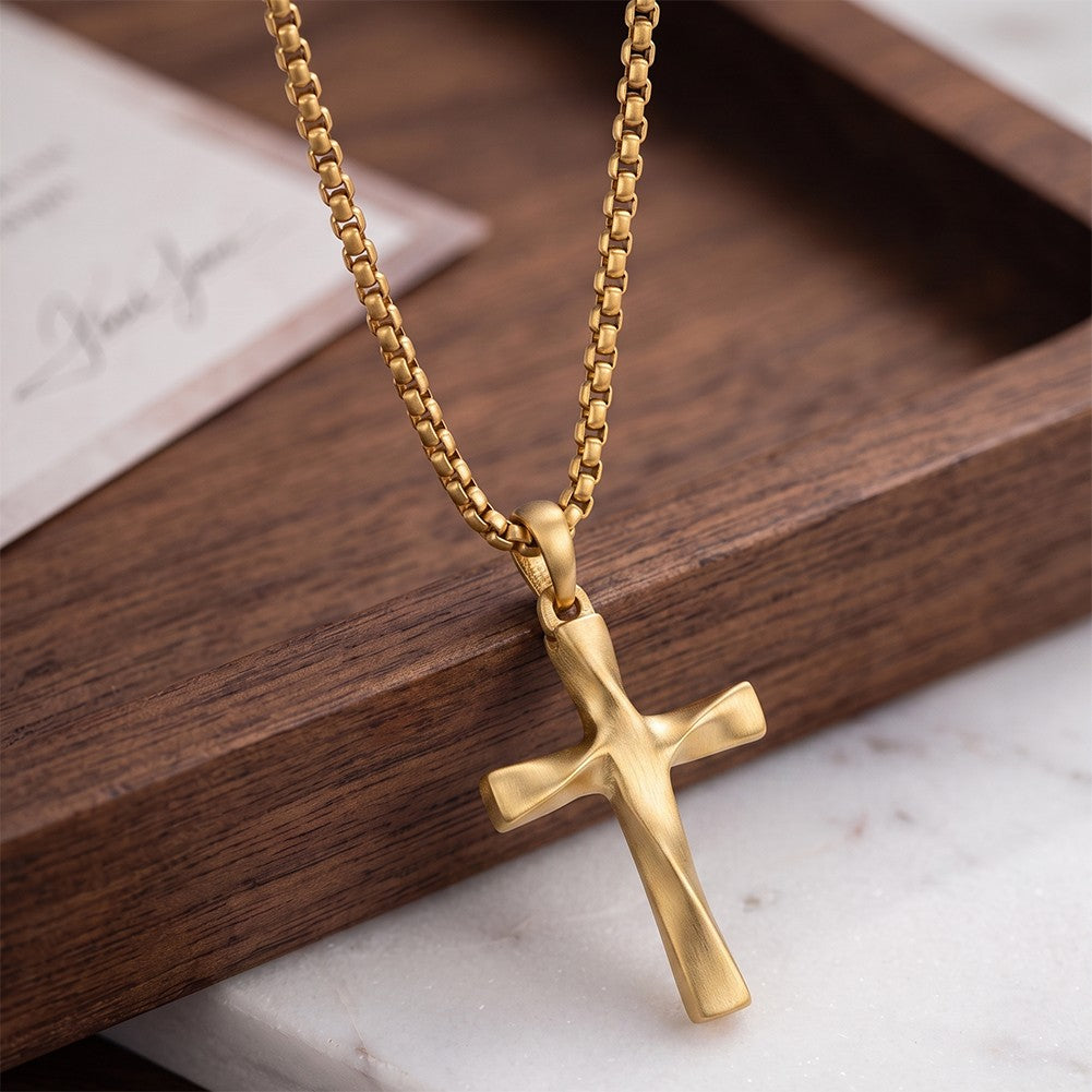 Close-up of the brushed gold cross and bail on a wooden tray