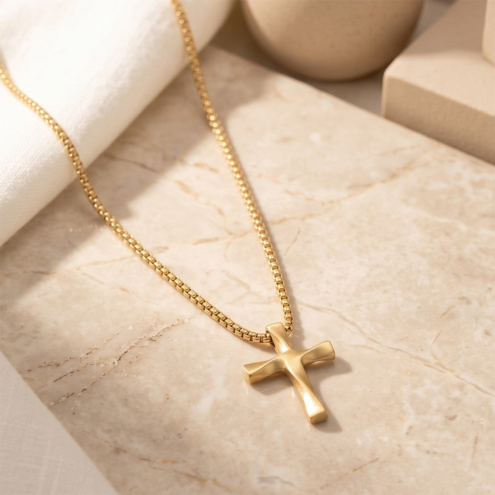 Gold Wavy Cross Pendant with chain laid on marble